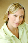 A blonde woman wearing a light green collared shirt looks toward the camera.