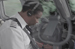 A person in a light-colored uniform and headset operates machinery or controls.