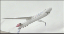 A white commercial airplane ascending into a gray, overcast sky.