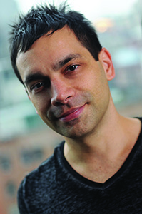A man with dark, spiked hair and a slight smile looking toward the camera.