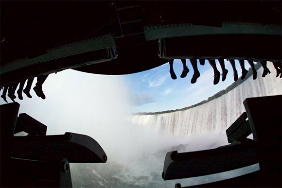 A wide waterfall with heavy mist viewed through a dark, silhouette-like structure.