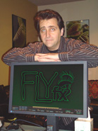 A man in a striped shirt leans over a computer monitor showing a green 'FLY fx' logo.