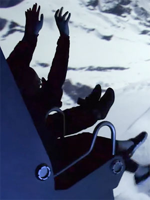 A person in dark clothing sits with arms raised against a bright, snowy landscape.