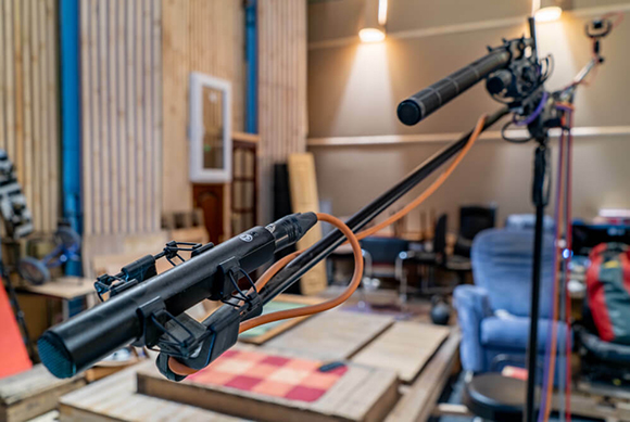 A black camera jib arm extends across a studio with a camera mounted on the end.