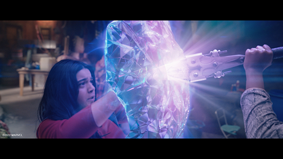 A person holds a large, glowing purple crystal object being struck by a metallic staff.