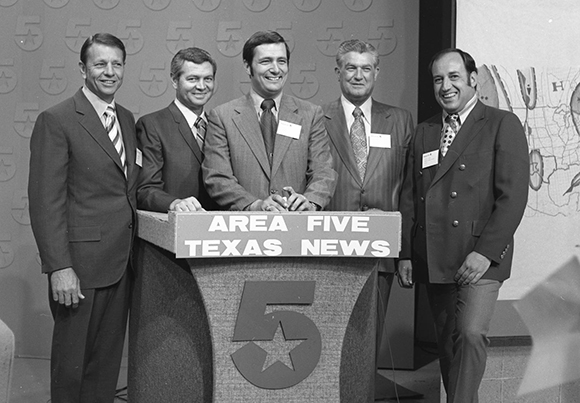 Five men in suits stand behind a news desk that reads Area Five Texas News.