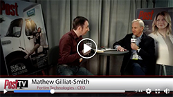Two men sit at a small table for an interview between two large posters.
