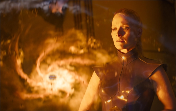 A woman in bronze armor looks toward a swirling vortex of orange fire and light.