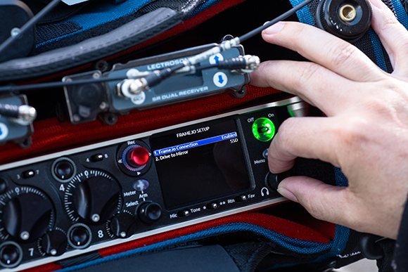Hands adjusting knobs and buttons on a professional audio mixer and receiver setup.