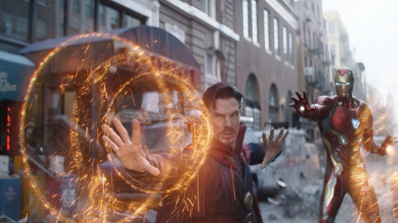 Doctor Strange uses glowing orange magic circles while Iron Man stands ready in a damaged city street.