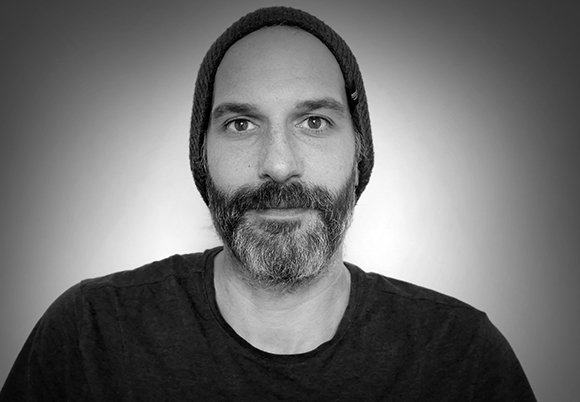 Black and white close-up portrait of a man with a beard and a beanie.