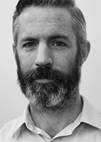 Black and white headshot of a man with short hair and a full beard looking directly at the camera.