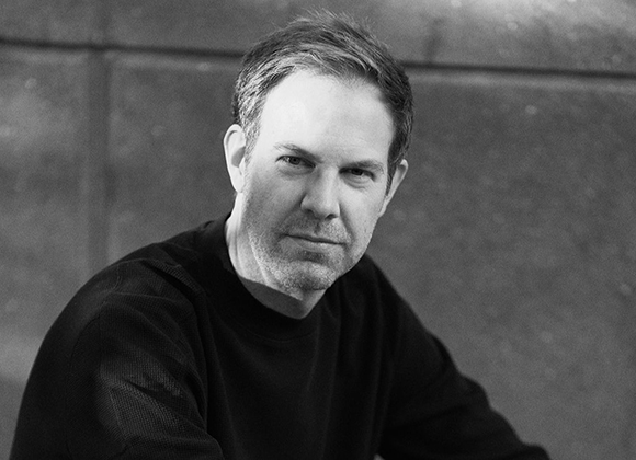 Black and white portrait of a man with short hair wearing a dark sweater.