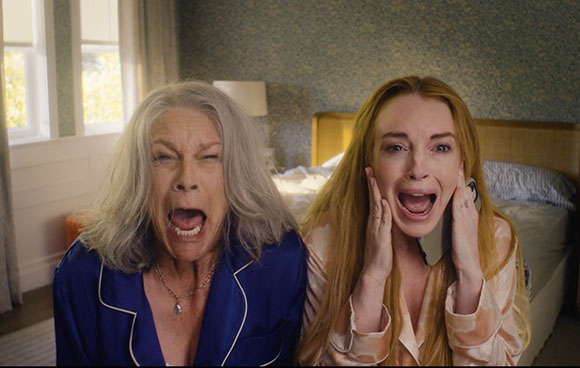 An older woman in blue pajamas and a younger woman in peach pajamas both have wide-open mouths in shock.