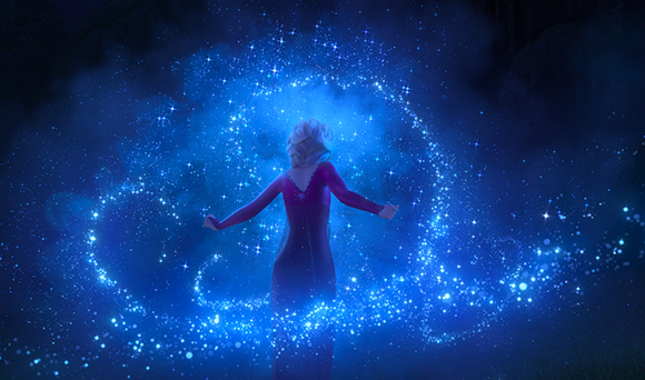 A woman in a purple dress stands with arms outstretched as glowing blue magical swirls surround her.