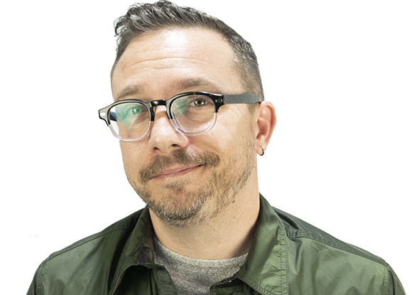 A man with short dark hair, glasses, and a goatee wearing a green button-down shirt.