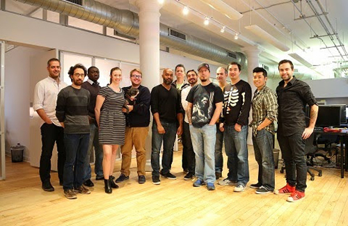 A diverse group of ten people standing together in a bright, modern open-plan office.