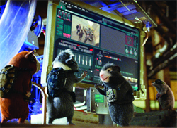 Three small rodents in gear stand before a large, glowing control monitor in a dimly lit setting.