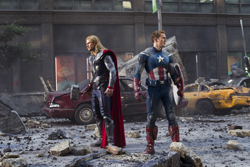 Thor and Captain America stand in a debris-filled city street with a wrecked car behind them.