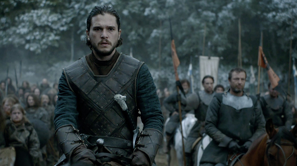 A man with dark hair and a beard wears dark leather armor while riding a horse through a wooded area.