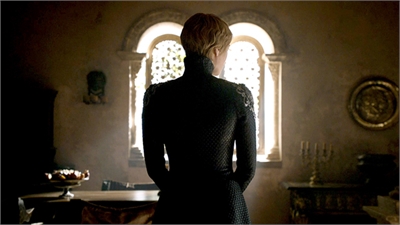 A woman in a dark, patterned dress stands with her back to the camera, facing a bright arched window.