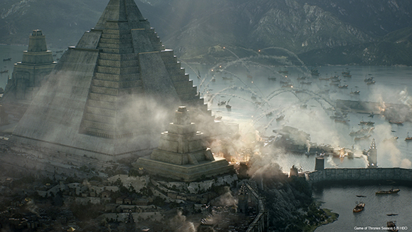 A large stone pyramid rises above a misty coastal city with many ships in the water.
