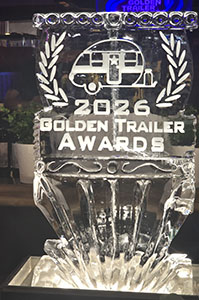 A clear crystal trophy featuring a camper icon and the text 2026 Golden Trailer Awards.