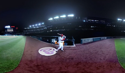 A baseball player in a white uniform stands in the batter's box at a stadium under bright lights at night.