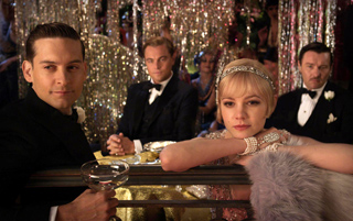 Four people in formal evening wear sit at a table amidst shimmering gold tinsel decorations.