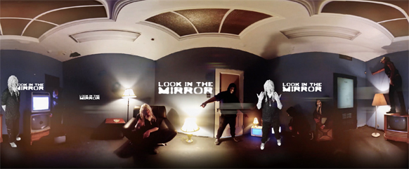Panoramic view of a dark room with people, lamps, and 'LOOK IN THE MIRROR' text on the walls.