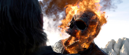 A flaming skull with an open mouth facing a person with dark hair from behind.