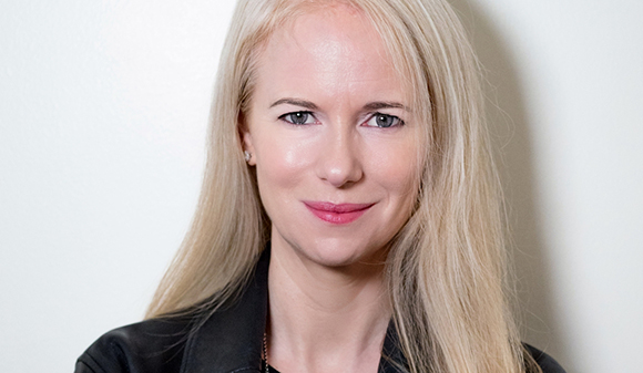 A blonde woman with blue eyes and a slight smile looking toward the camera.