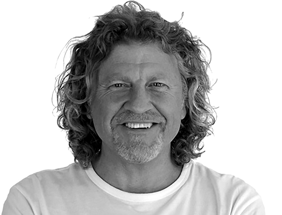 Black and white headshot of a smiling man with wavy, shoulder-length hair and a goatee.