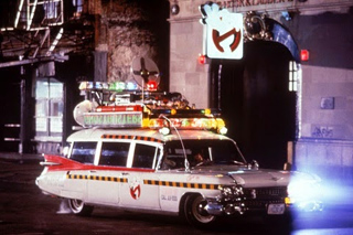 A white vintage car with a complex array of colorful lights and equipment mounted on its roof.