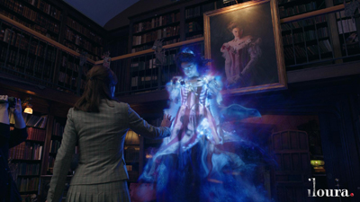 A person in a grey suit observes a glowing, ethereal blue figure standing before a framed portrait.