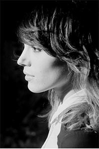 Black and white profile portrait of a woman with long, wavy hair looking to the left.