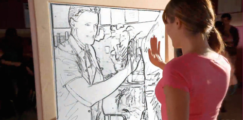 A person in a pink shirt places their hand against a large line drawing of a person.