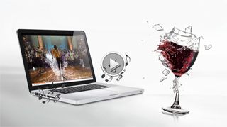 A laptop shows a video of people dancing while a glass of red wine shatters nearby amidst musical notes.