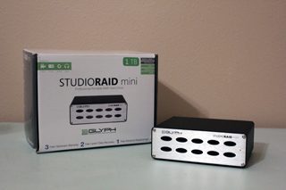 A white box for a StudioRAID mini and the black portable RAID hard drive sitting next to it.