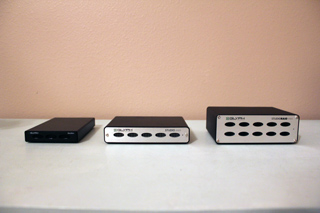 Three black rectangular electronic devices of different sizes arranged in a row on a white surface.