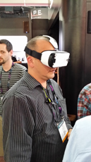 Man wearing a white Samsung Gear VR headset with black straps, looking to the right.
