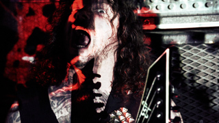 A man with long curly hair and a beard shouts intensely under red lighting.