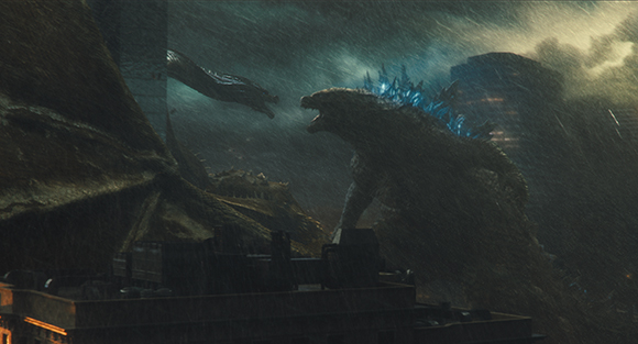 A giant reptilian monster with glowing blue dorsal fins faces a long-necked creature in a dark rainstorm.