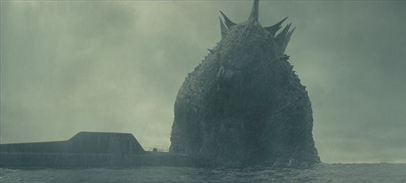 A giant, textured sea creature with dorsal spikes emerges from the ocean near a submarine in the rain.