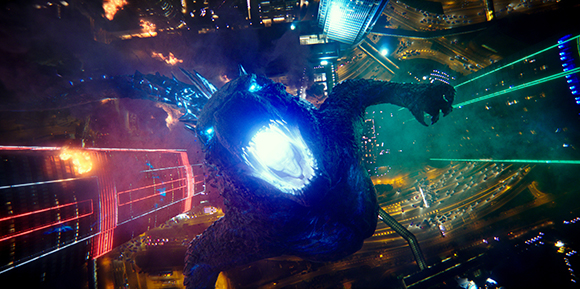 A massive, dark creature with a glowing blue mouth and eyes looms over a brightly lit city at night.