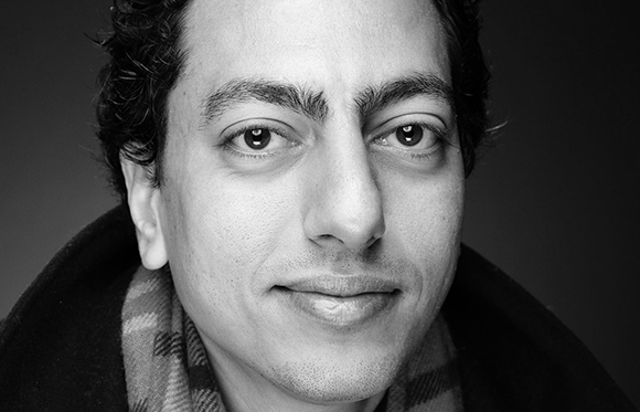 Black and white close-up portrait of a man looking directly at the camera.