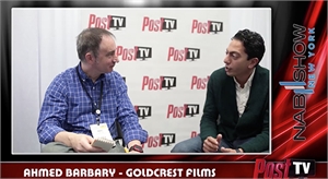 Two men sit facing each other for an interview in front of a white backdrop with red Post TV logos.