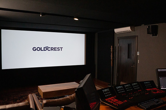 A large white projection screen with the word GOLDCREST in dark letters in a dimly lit room.