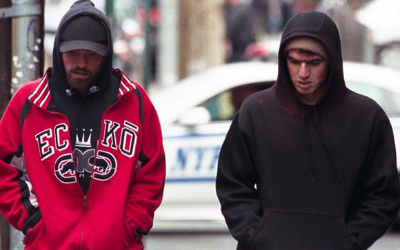 Two men walking side by side wearing dark hoodies, one in a red ECKO sweatshirt.