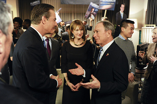 Several people in business attire talking in a brightly lit indoor setting.